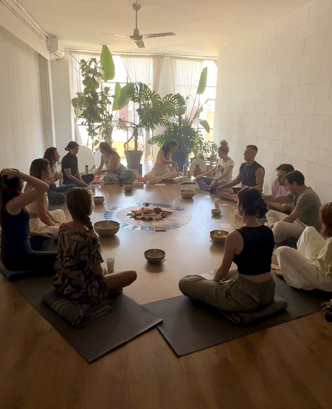 Roda de participantes sentados em volta de uma mandala, em uma sala clara
