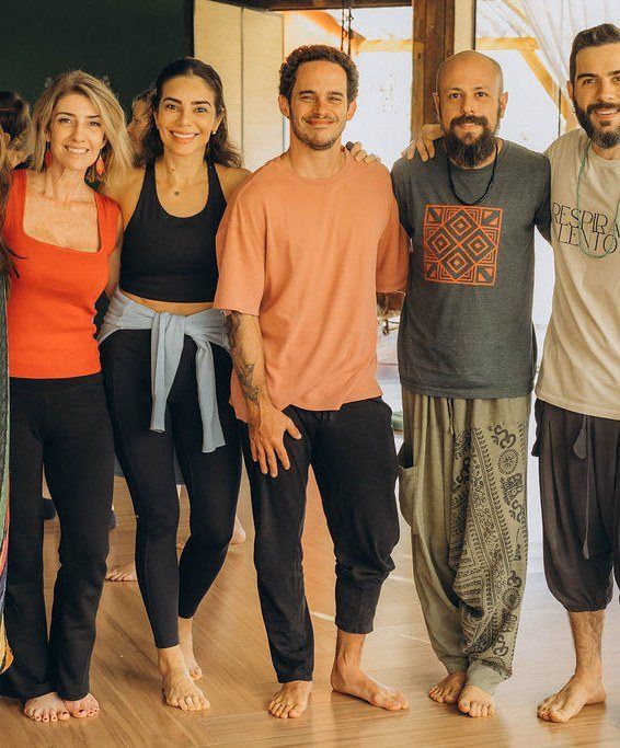 Elini lado a lado com o grupo de facilitadores, em uma sala de madeira